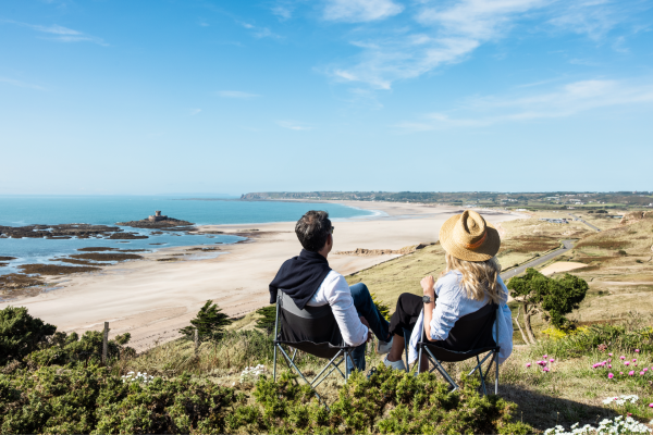 A couple sitting on the sand dunes over looking st ouens bay