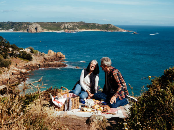 Couple having a picnic on a headland overlooking the sea
