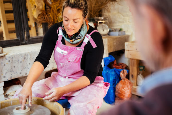 Woman in overalls at a pottery wheel