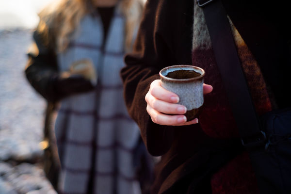 Woman holding a handmade mug on the beach