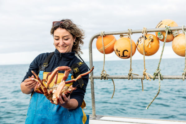 Young fisherwoman holding a crab on board a boat