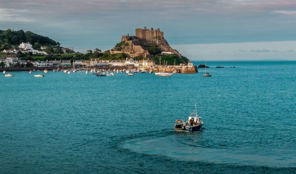 Fishing boat on the water in front of a medieval castle in Gorey, Jersey