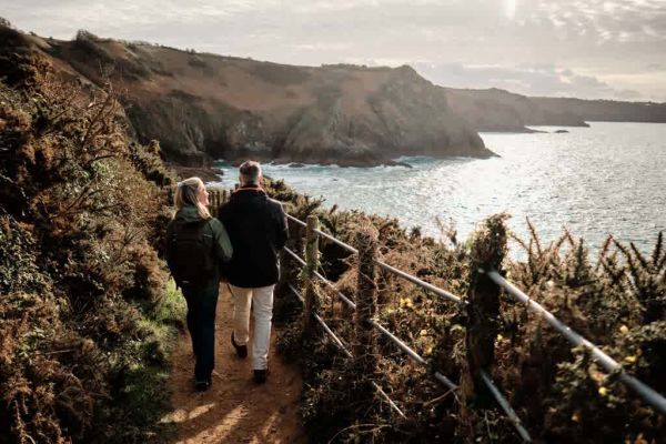 Couple walking along a dramatic stretch of coastline with moody skies