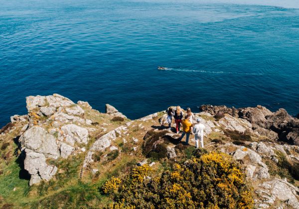 People standing on cliff path headland overlooking the sea