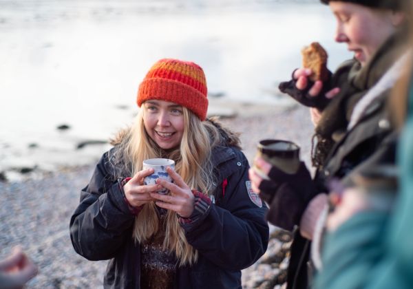 Girl drinking a warm drink by the sea