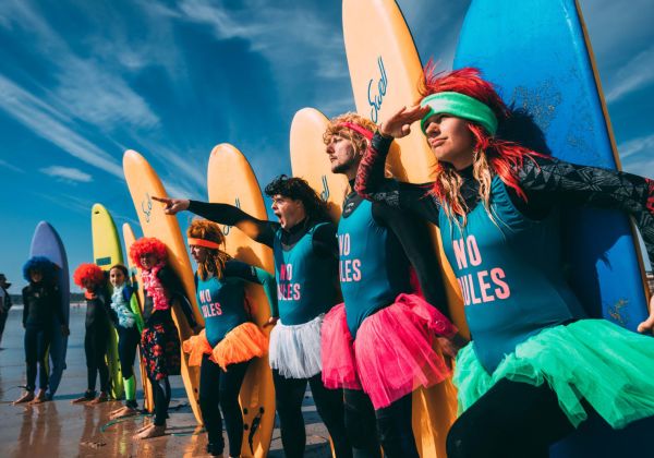 surfers holding surfboards dressed in 80s themed outfits