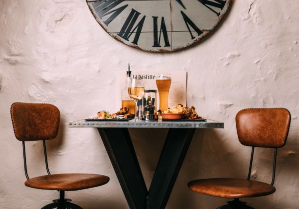 A photo of a table and two drinks. There is a rustic clock above.