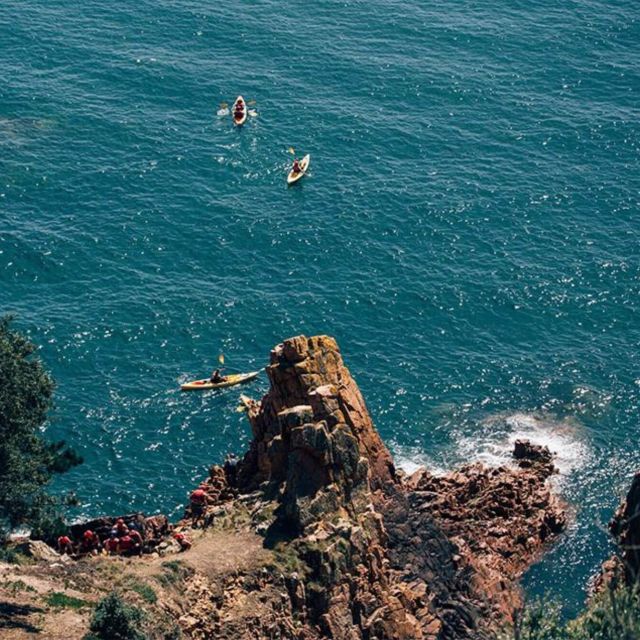 Kayakers about to enter a sea cave from the view of a cliffside.