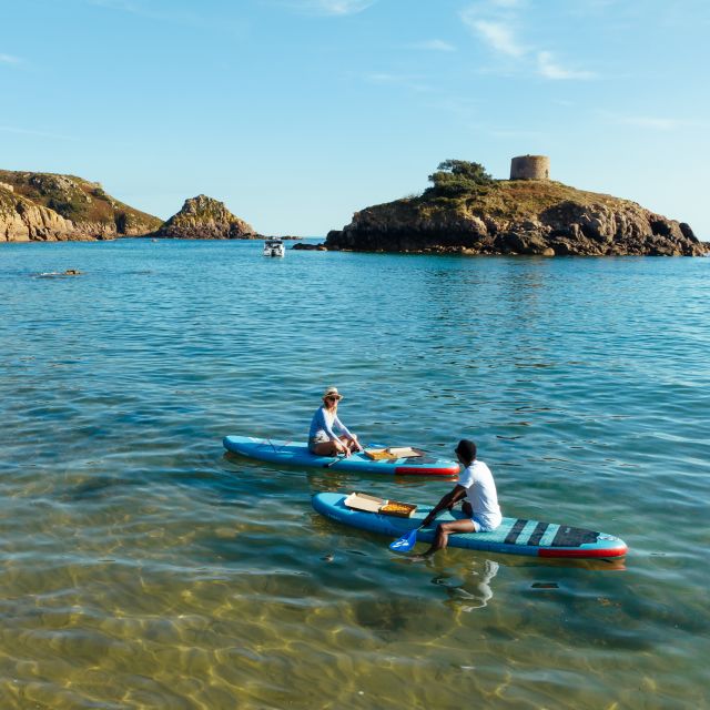 Couple sitting on paddle boards on turquoise sea