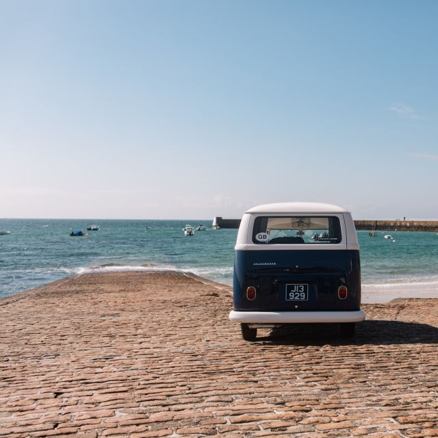 Classic campervan parked on La Rocque beach slipway facing out to sea.