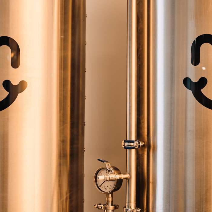 A picture of fermenting vats for beer with the Bliss Brew Co. Logo on it (the logo is a smile)