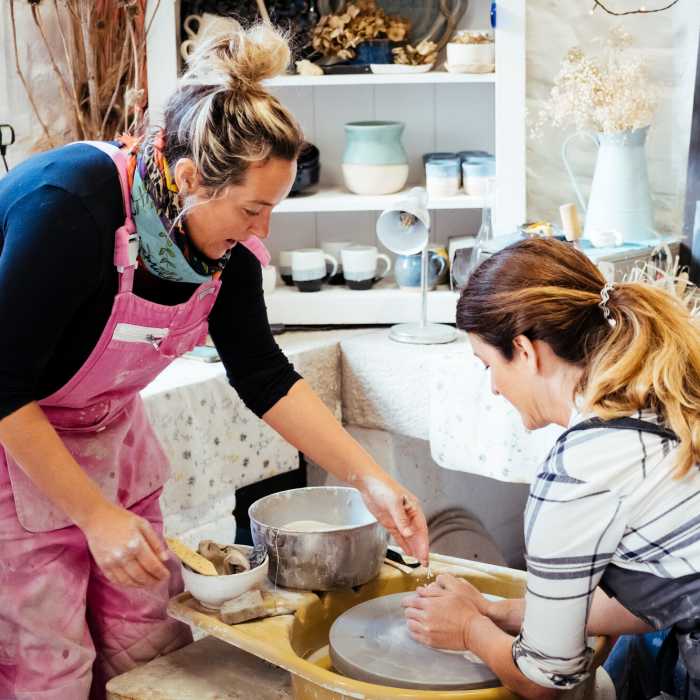 Ceramacist teaching someone how to use the wheel