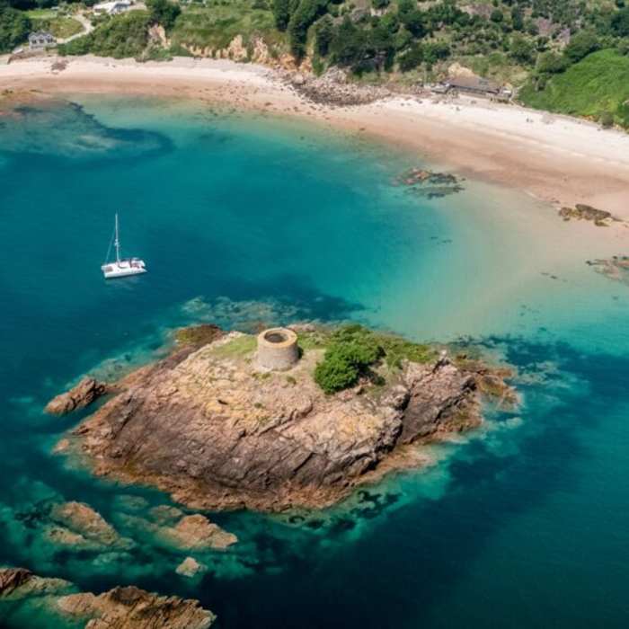 Areial shot of Janvrin's Tomb and Portelet Bay, surrounded by turquoise waters
