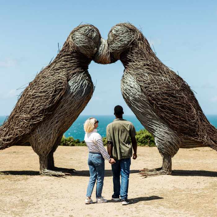 Young couple admiring the puffin sculptures at Plemont, Jersey