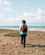 Woman walking on beach with back pack